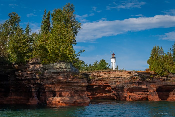 White lighthouse on a rocky island with trees