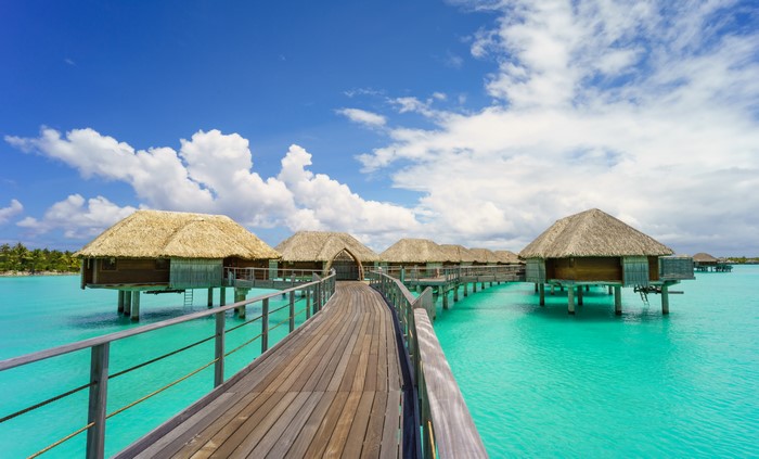 Overwater bungalows with thatched roofs in turquoise water