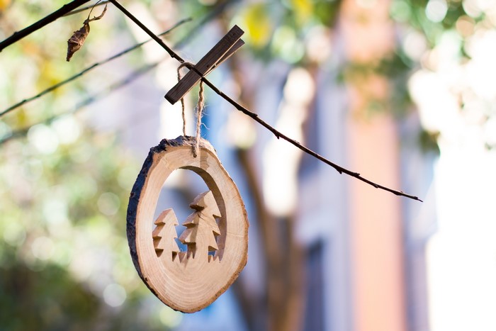 Wooden Christmas ornament with trees hanging on a branch