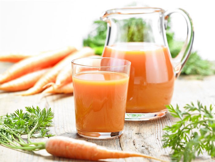 Carrot juice in a glass and jug with carrots