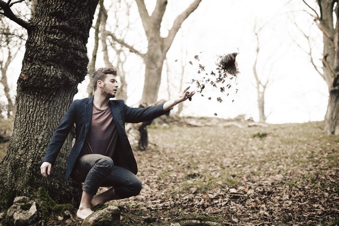 Man in a suit throwing leaves in a forest