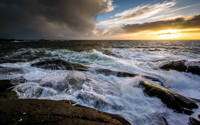 Waves crashing on rocks at sunset