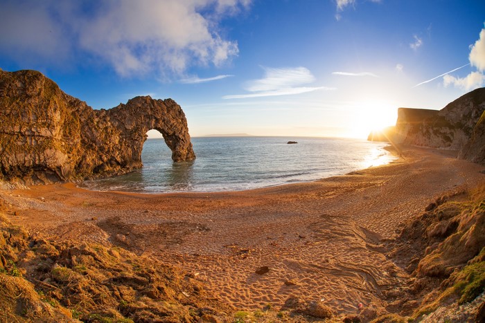 Durdle Door rock arch on a beach at sunset