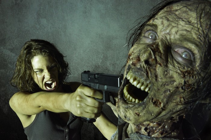 Maggie from The Walking Dead aims a pistol at a zombie