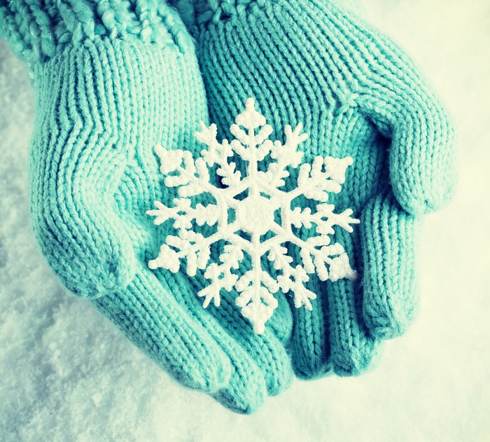 Hands in mittens holding a snowflake