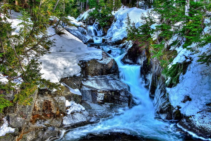 Snowy waterfall cascading over rocks in a forest