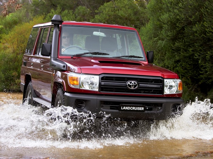 Red Toyota Land Cruiser 76 driving through water