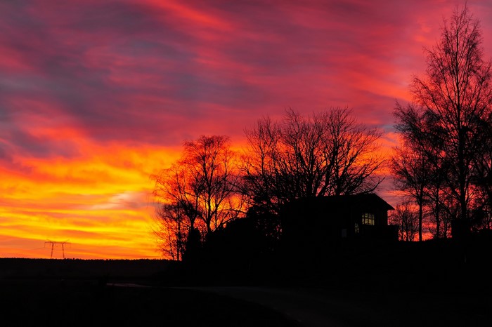 Silhouette of a house and trees against a vibrant sunset