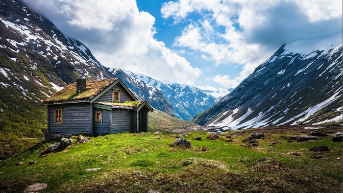 Wooden cabin with grass roof in a mountain valley