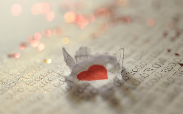 Torn paper with red heart on handwritten page
