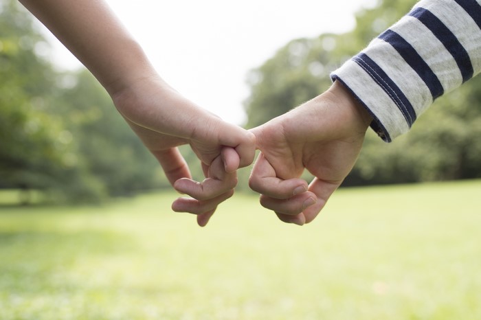 Two people pinky promising in a park