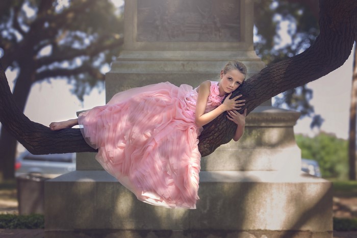 Girl in pink dress on tree branch