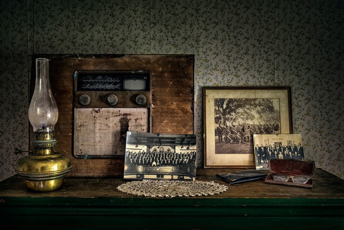 Antique radio, kerosene lamp, and photographs on a dresser
