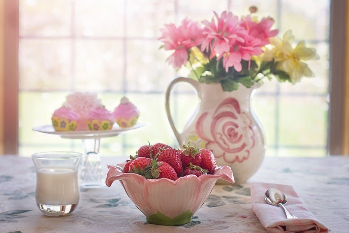 Still-life with strawberries, cupcakes, milk, and flowers
