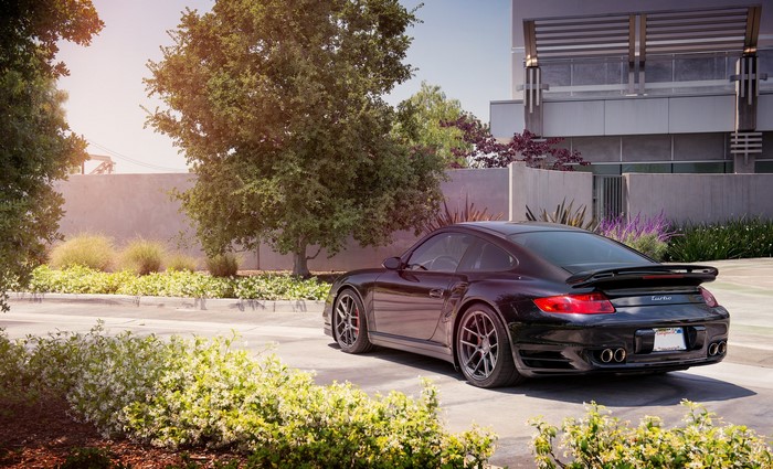 Black Porsche 997 Turbo parked near a modern building