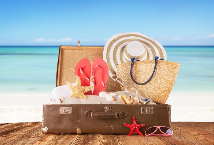Suitcase with beach items on a wooden table