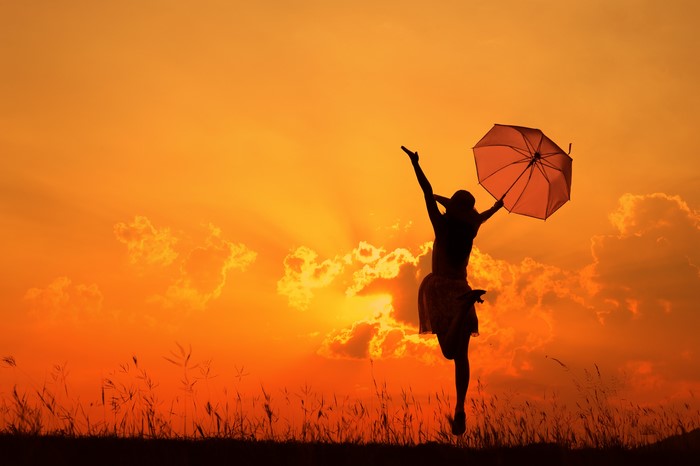 Silhouette of a person with an umbrella at sunset