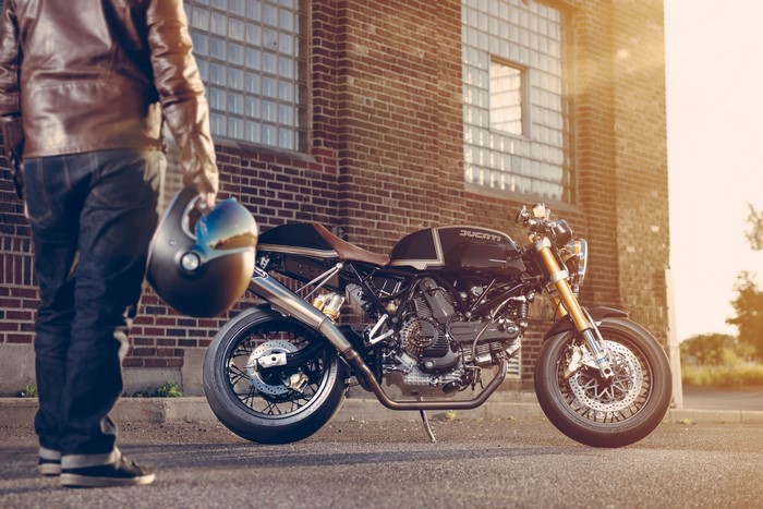 Man holding helmet next to Ducati Sport 1000SE motorcycle
