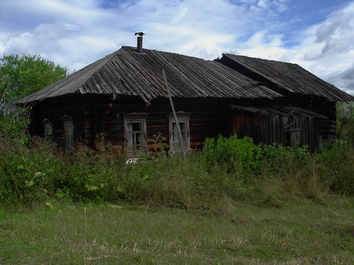 Abandoned wooden house with overgrown vegetation