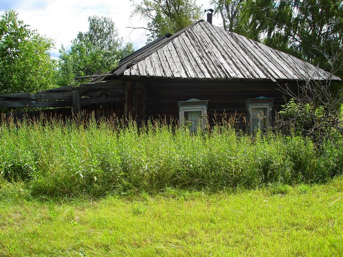 Old wooden house with overgrown grass and fence