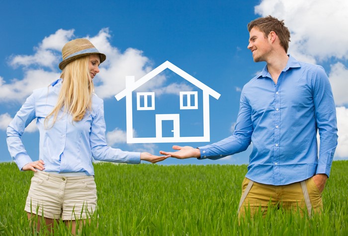 Couple holding a house icon in a field
