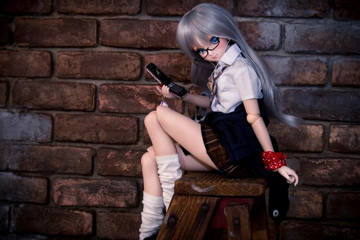 Doll with glasses holding a flip phone