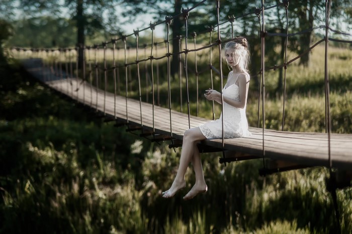 Woman sitting on a suspension bridge