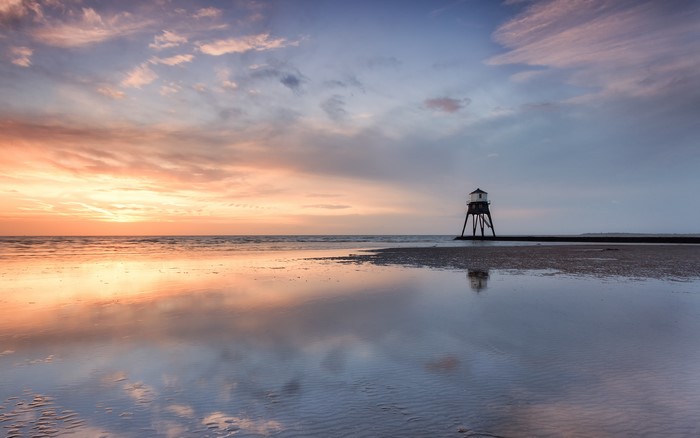 Lighthouse on a beach at sunset