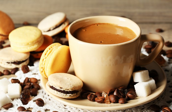 Coffee cup with macarons and coffee beans