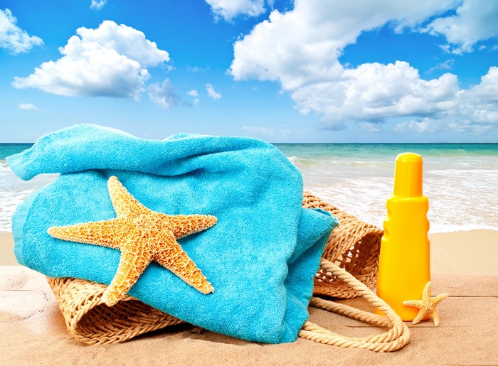 Summer beach scene with towel, starfish, and sunscreen