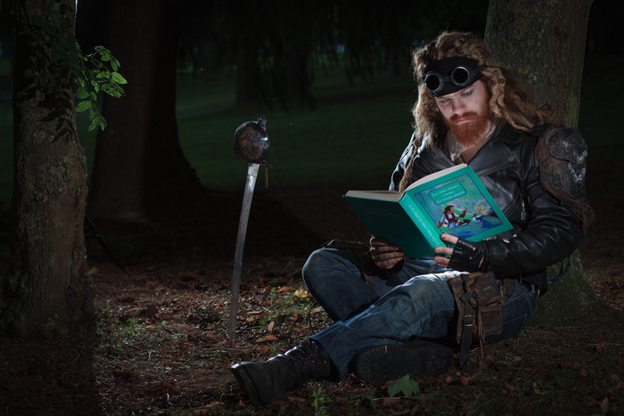 Man with sword reading a book in the forest