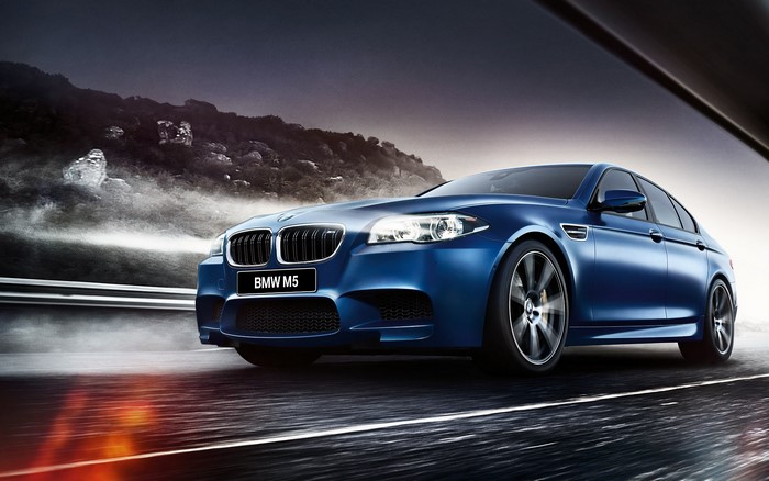 Blue BMW M5 F10 Sedan driving on a road