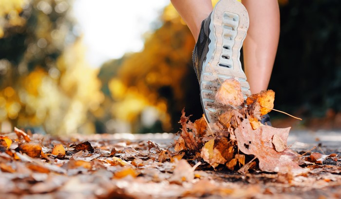 Running shoe stepping on autumn leaves