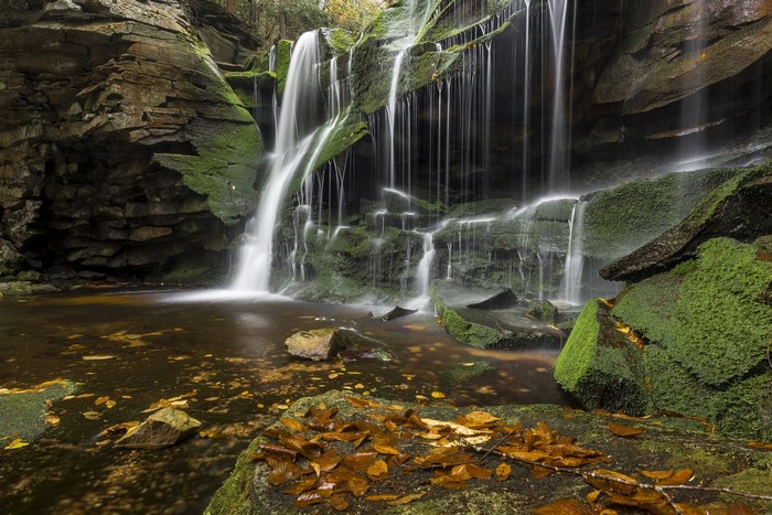 Waterfalls cascading over moss-covered rocks in autumn
