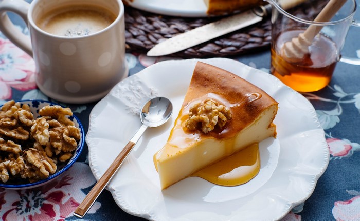 Slice of cheesecake with walnuts and honey, coffee, and nuts