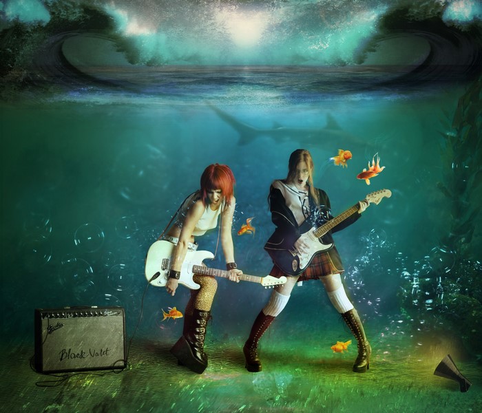 Two girls playing guitars underwater with sharks and fish