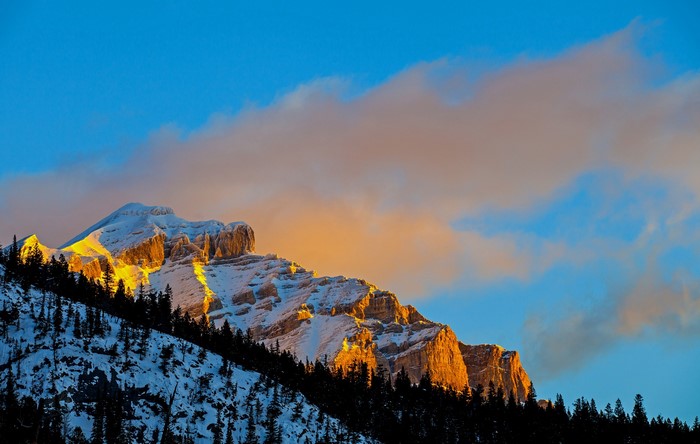 Snow-covered mountain peak illuminated by golden sunlight