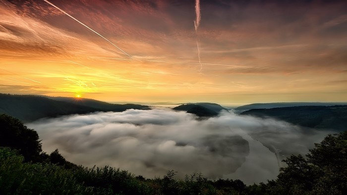 Sunrise over a foggy river valley with mountains