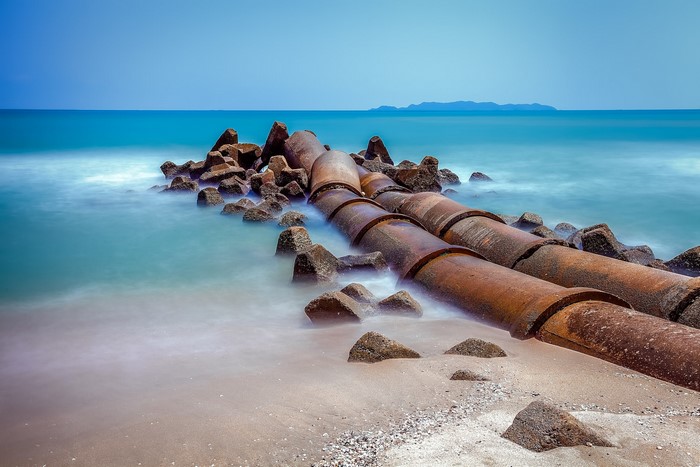 Rusty pipes and tetrapods on a beach with the sea