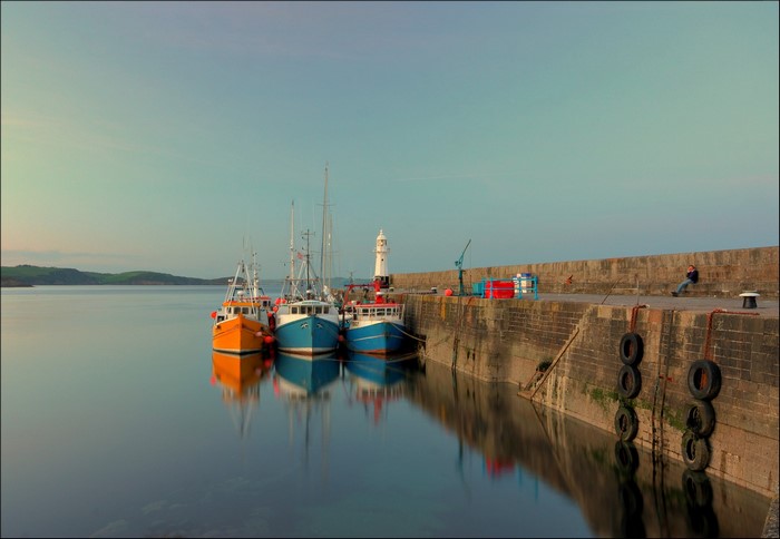 Fishing boats docked at a harbor with a lighthouse