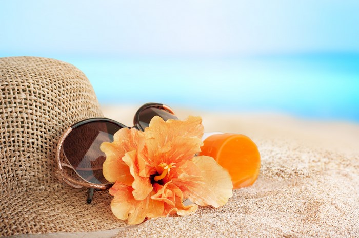 Summer beach accessories: hat, sunglasses, flower, and sunscreen