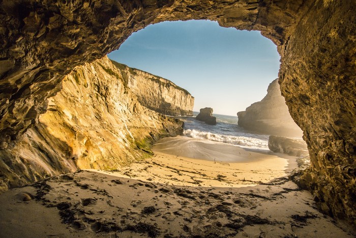 Cave opening to a beach with cliffs and ocean