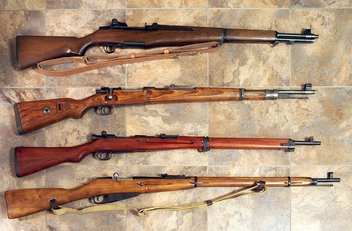 Four vintage rifles displayed on a tiled surface