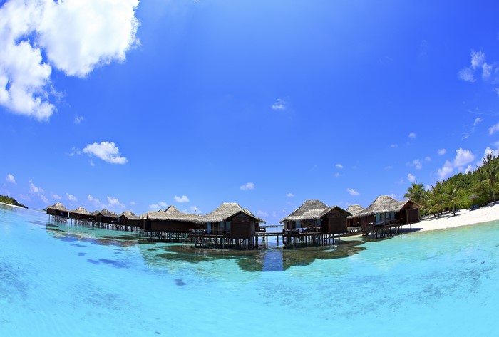 Overwater bungalows in the Maldives under a blue sky