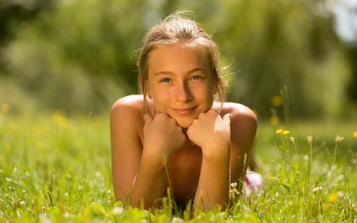 Young girl lying in grass on a sunny day