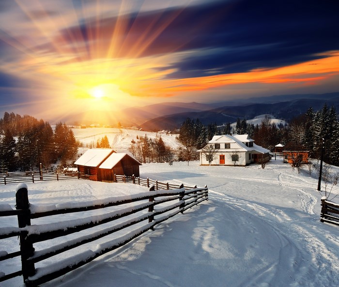 Winter village with sun rays over snow-covered landscape
