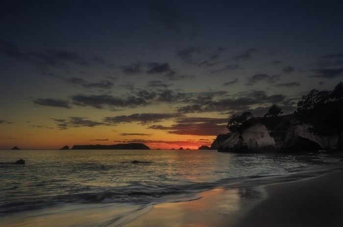 Sunset over the ocean with rocky islands and beach