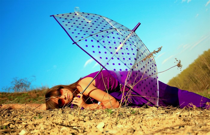 Woman with umbrella lying on the ground