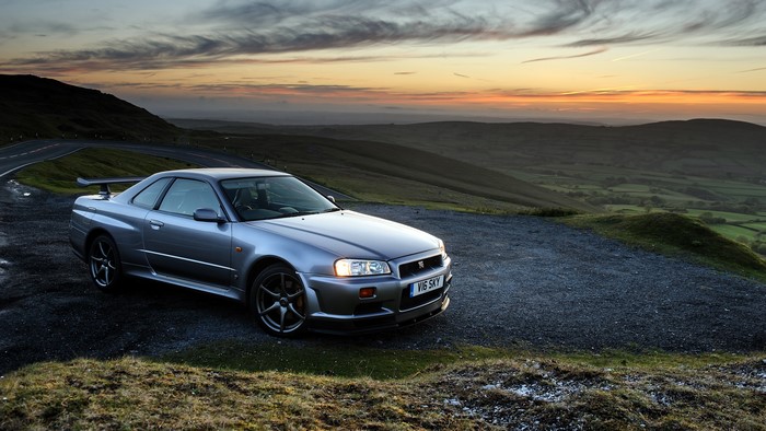 Nissan Skyline GT-R V-spec BNR34 on a mountain road at sunset