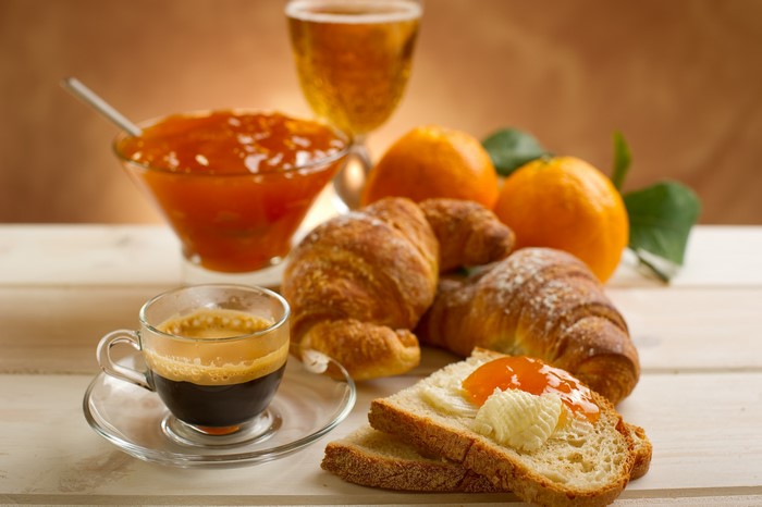 Breakfast with Croissants, Coffee, Jam, and Oranges